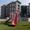 Tot lot playground with red slides on artificial turf