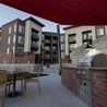 Outdoor grilling area with dining tables and shade sail