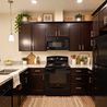 Staged kitchen with dark cabinets and black appliances