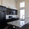 Kitchen with dark cabinets, granite island, and black appliances